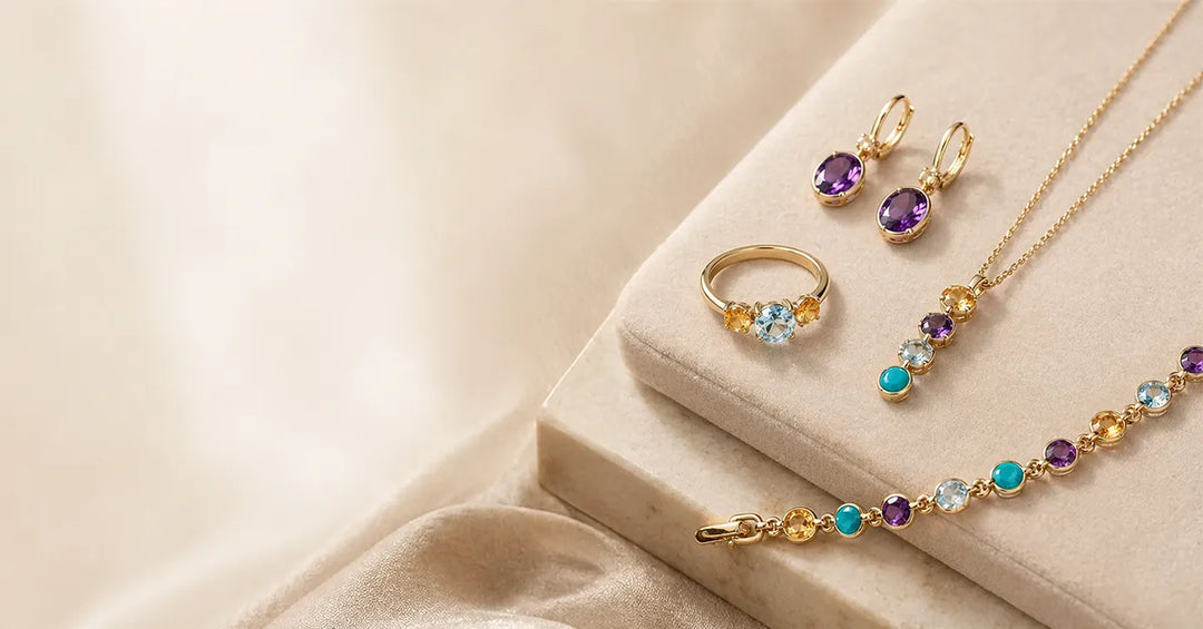 Златни бижута за зодия Стрелец върху светла елегантна повърхност – обеци с аметист, пръстен с цветни камъни, колие и гривна с топаз, цитрин и тюркоаз