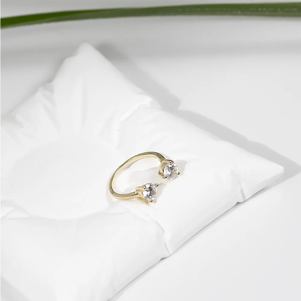 Златен пръстен с два циркона върху бяла възглавничка в lifestyle кадър