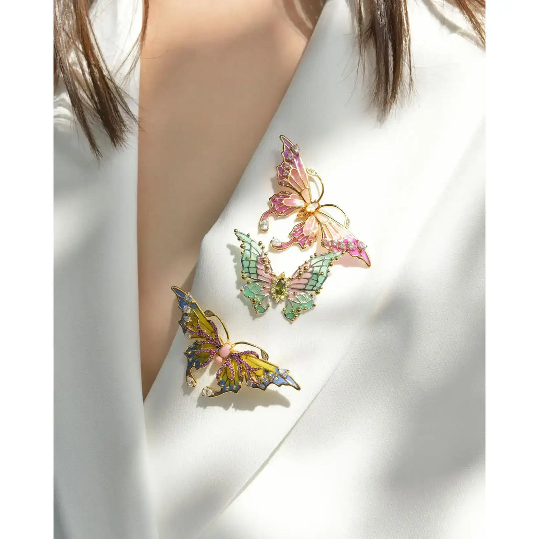 Модел носи брошка пеперуда със зелен и розов емайл и циркони върху сако
