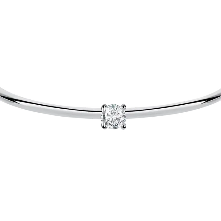 Близък план на кръгъл бял циркон в четиризъбов обков върху сребриста гривна.