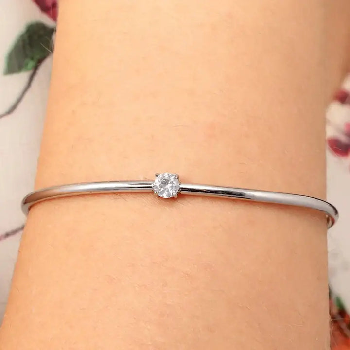 Сребриста гривна с бял циркон върху китка на модел, портрет.