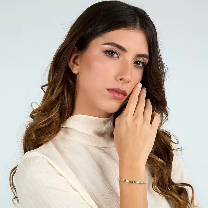 Гривна със зелени циркони 3×3 мм върху китка на модел, портрет.
