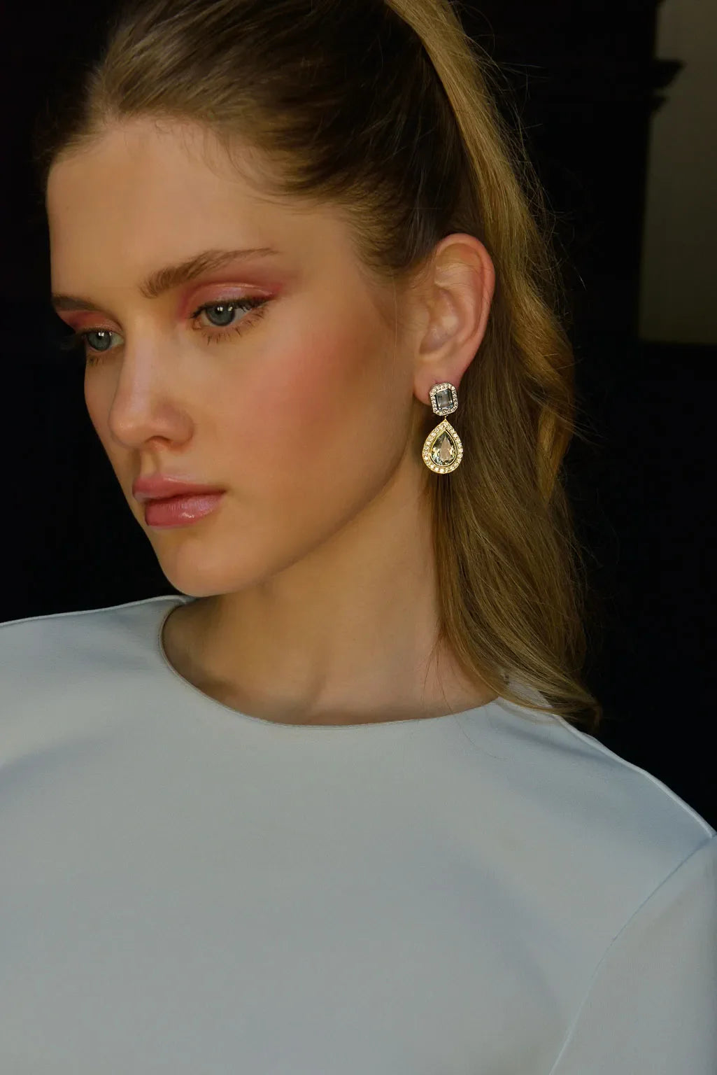 Близка снимка на обеци Salvatore Plata с аметист и топаз, поставени на жена с руса коса.