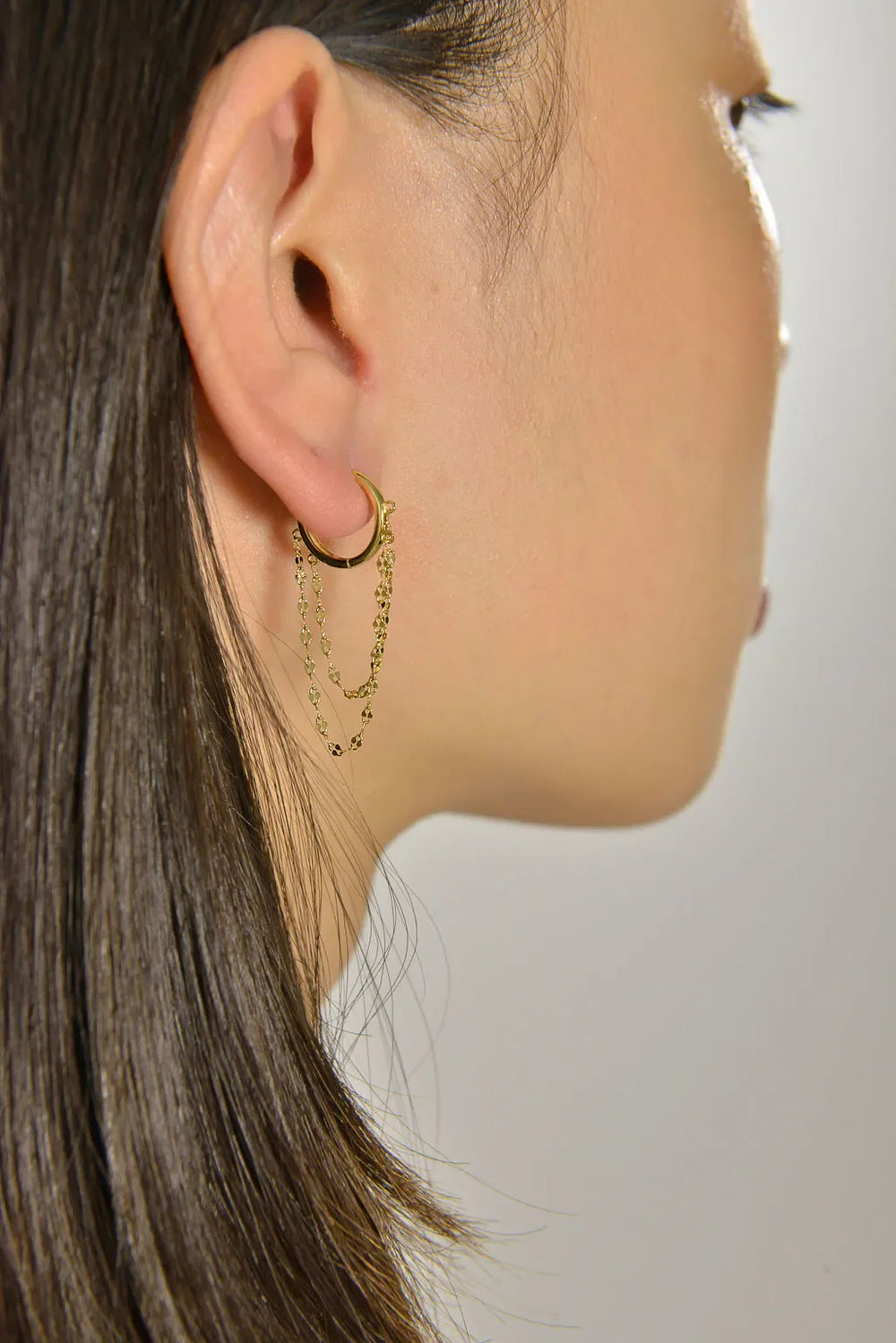 Детайлен поглед към дамска обеца Salvatore Plata с позлатена верижка, носена от жена с тъмна коса.