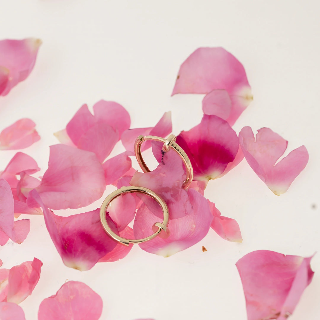 Дамски златни обеци халки на розов фон.