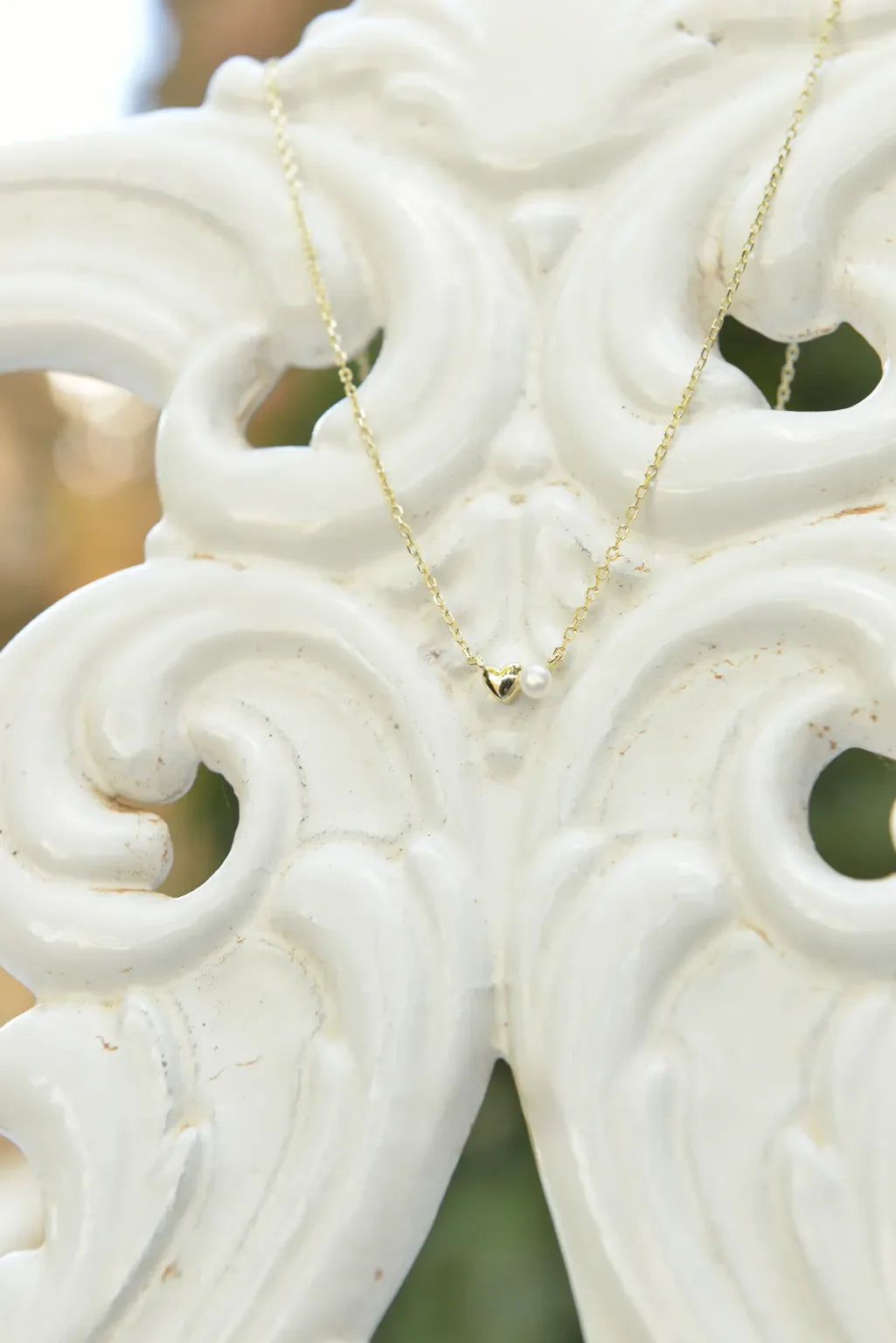 Детайлна снимка на колие Salvatore Plata с позлатен сърцевиден елемент и перла.