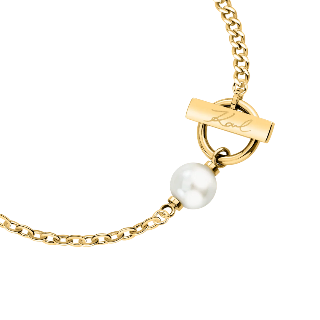Детайлен кадър на дамска гривна Karl Lagerfeld със златист елемент с подпис Karl и бяла перла – KLAYR13
