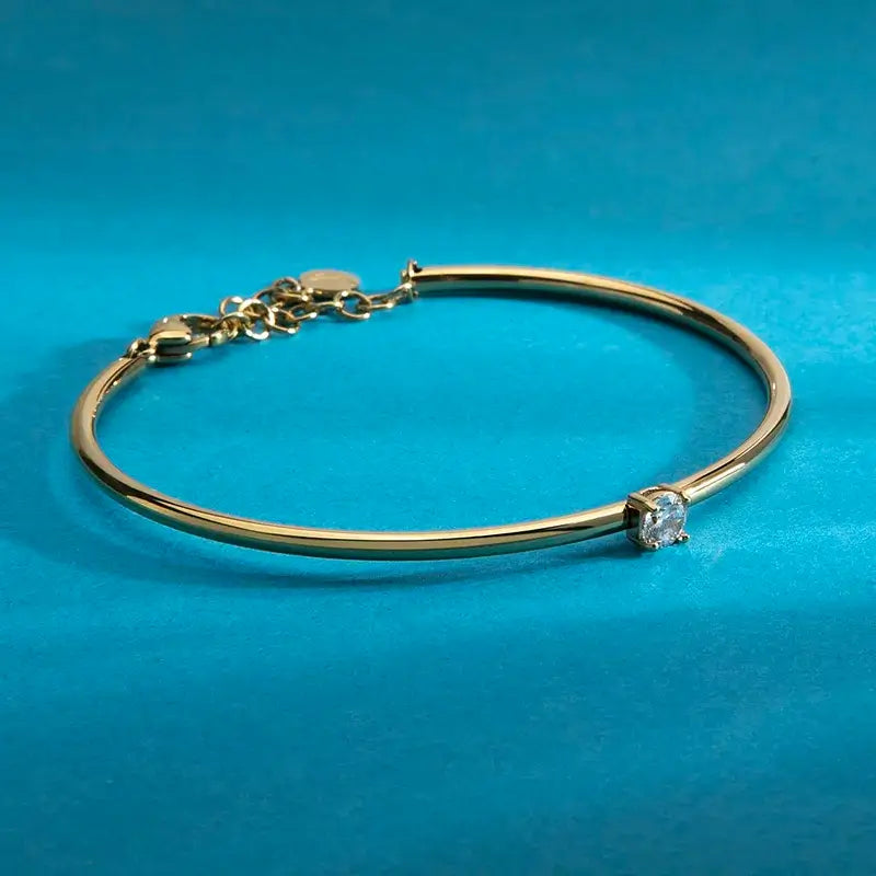 Позлатена твърда гривна с бял циркон върху китка на модел, портрет.