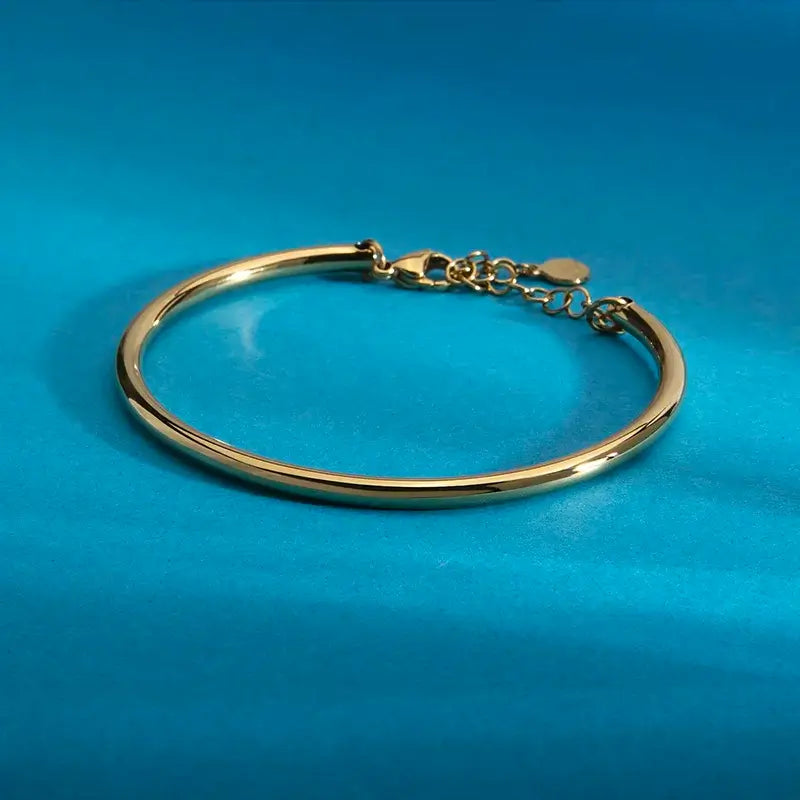 Страничен профил на тънка позлатена твърда гривна, огледален блясък.