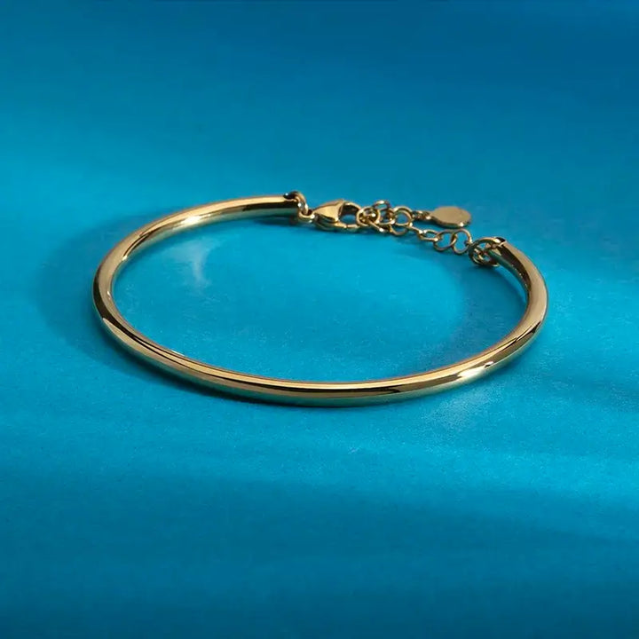 Страничен профил на тънка позлатена твърда гривна, огледален блясък.