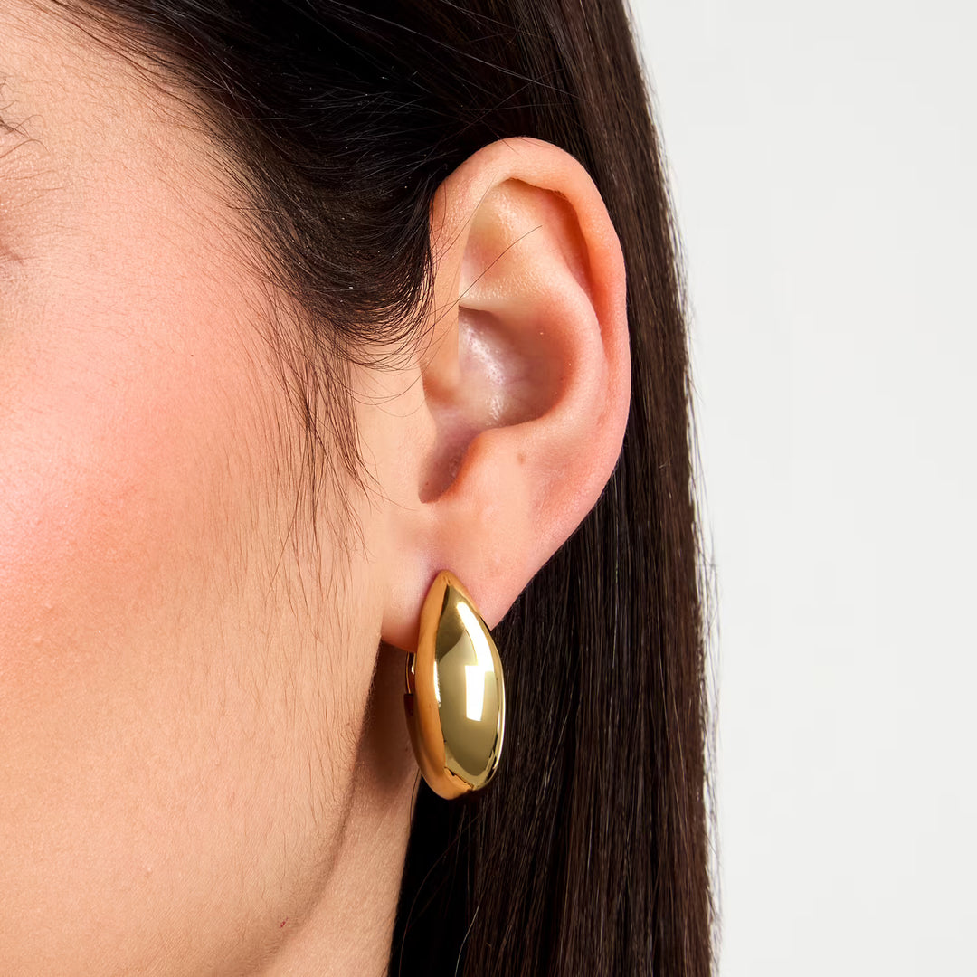 Близък план на овална позлатена халка със златно PVD, върху ухото, SAUP32.
