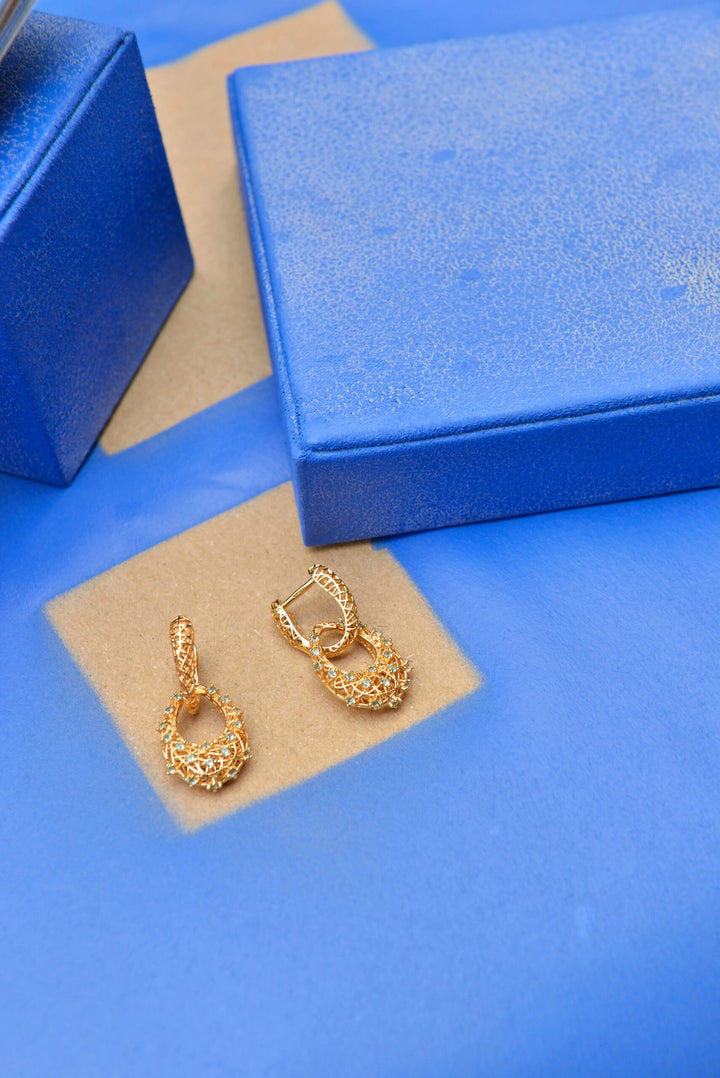 Gold-plated silver earrings with interwoven lines and Paraiba-colour CZ Salvatore Plata — jewellery composition