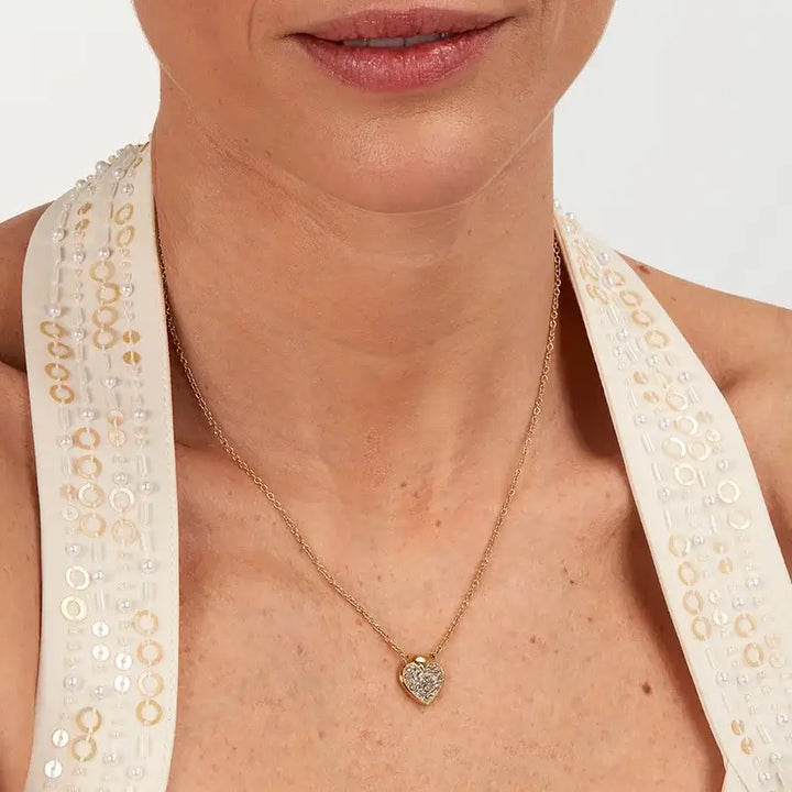 Близък план на висулка сърце с кристали на врата.