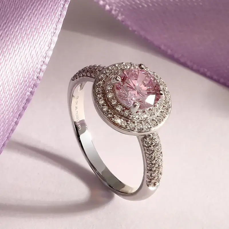 Лайфстайл кадър на пръстен „ореол“ с розов циркон върху светъл фон с лилава лента.