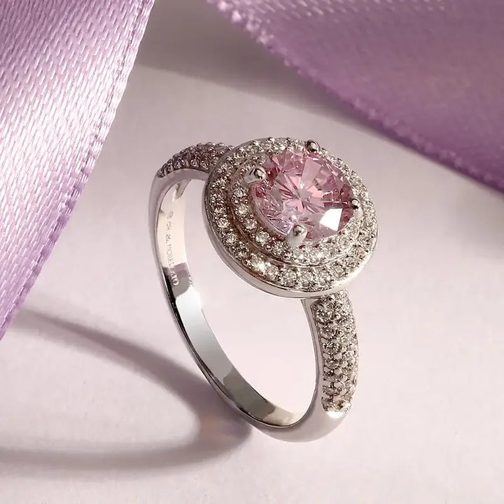 Лайфстайл кадър на пръстен „ореол“ с розов циркон върху светъл фон с лилава лента.