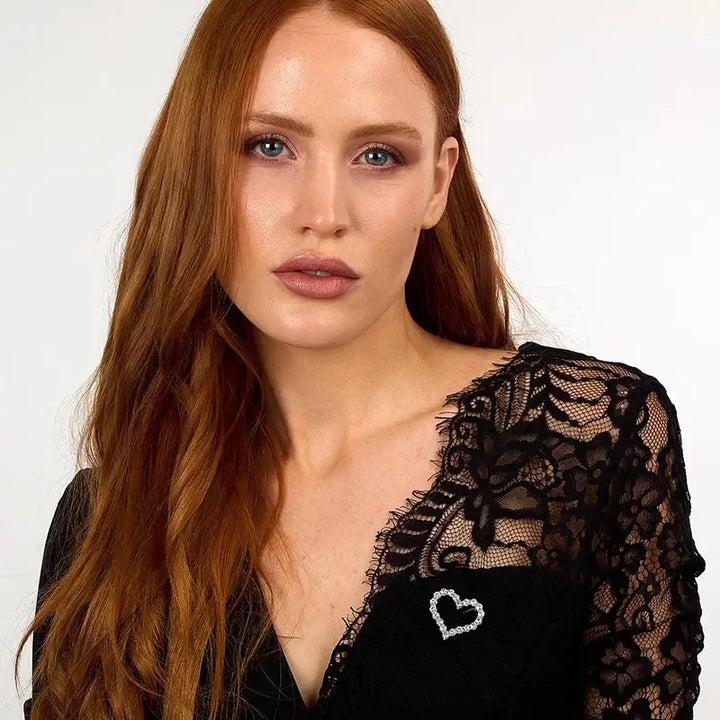 Сребърна брошка с бели циркони върху сако, портрет на модел.