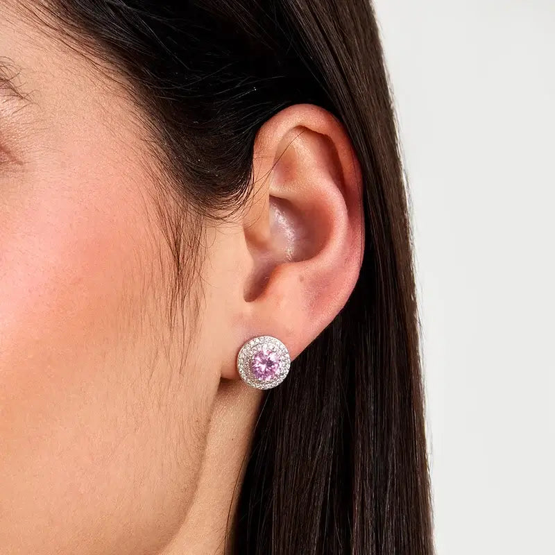 Близък план на ухо с обеца „ореол“ – розов център и бели циркони.