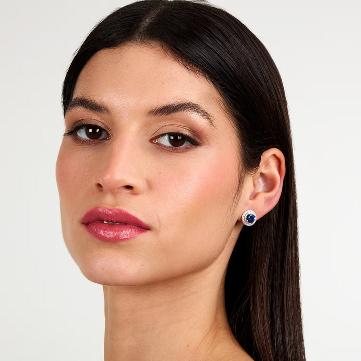 Обеци „ореол“ със син циркон върху ухо на модел, портрет.
