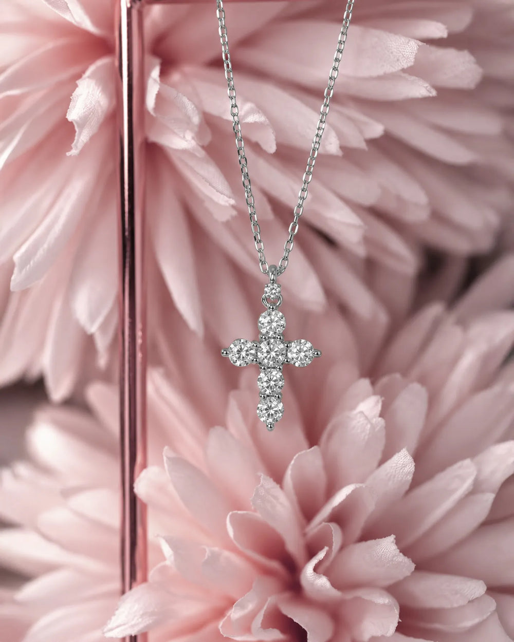 Сребърно колие с кръст от кръгли циркони Senso Silver, представено сред розови цветя