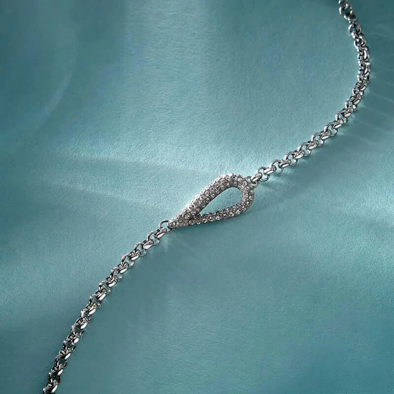 Лайфстайл кадър на сребриста гривна с висулка „капка“ върху светлосин фон.