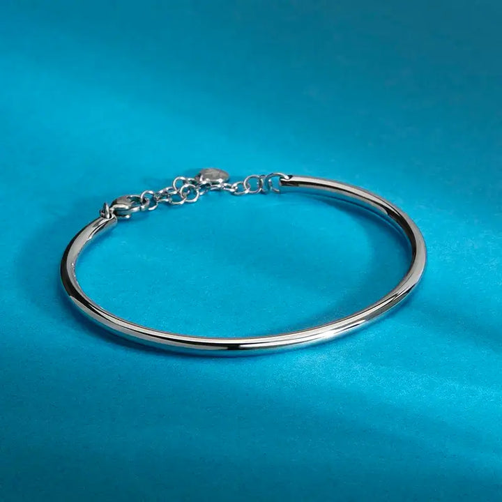 Страничен профил на тънка стоманена твърда гривна, огледален финиш.
