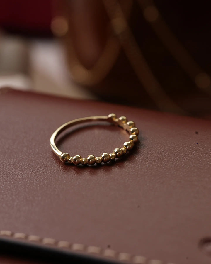 14K Polished Gold Bead Ring by Senso Gold, close-up on a brown surface